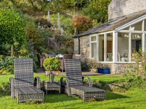 three wicker chairs and a table in front of a house at 4 Bed in Sedbergh SZ595 in Milnthorpe