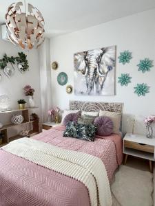 Un dormitorio con una cama rosa y un cuadro de un elefante. en Sevilla tu casa, en Espartinas