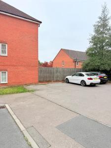 a white car parked next to a red brick building at Stylish Townhouse in Rugby, sleeps up to 9! in Rugby