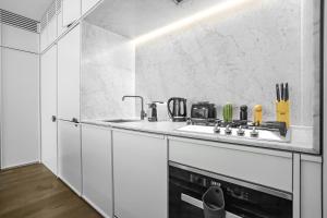 une cuisine blanche avec une cuisinière et un évier dans l'établissement Center of Sydney 2 Bedroom Apartment with Balcony, à Sydney 5 autres photos