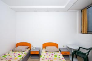 two beds in a room with a table and chairs at Lifto Hostel in Voyvodinovo