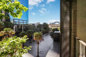 Elle offre une vue sur une cour avec des palmiers et des bâtiments. dans l'établissement Center of Sydney 2 Bedroom Apartment with Balcony, à Sydney