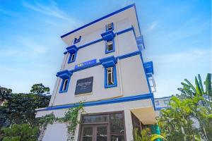 a tall white building with blue trim at Via PRG Park in Benaulim