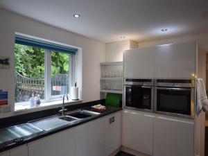 シモンズ・ヤットにある4 Bed in Symonds Yat 72538の白いキャビネット、シンク、窓付きのキッチン