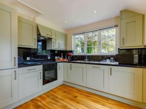 a large kitchen with white cabinets and a wooden floor at 1 bed in Cinderford 88272 in Cinderford