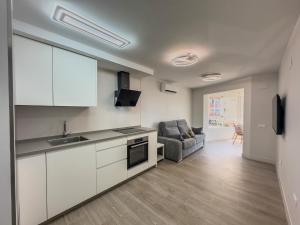 Castillo BajoにあるEstudio Mediterraneo A124の白いキャビネットとソファ付きのキッチンが備わります。