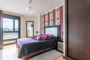 Un dormitorio con una cama con sábanas moradas y una ventana. en Apartamento Brétema, en Altamira