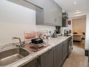 eine Küche mit Spüle und Abtropfgestell auf der Arbeitsplatte in der Unterkunft Highfield Cottage in Windermere