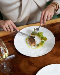 a person holding a knife and fork and a plate of food at Garden Suites with private Jacuzzi in Burgh Haamstede