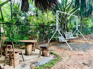 a group of tables and chairs and a swing at Villa Eco Stay in Tangalle