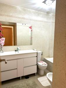 Un baño con lavabo, inodoro y espejo. en Sevilla tu casa, en Espartinas