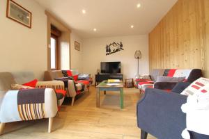a living room with couches and a flat screen tv at La Clé des Champs à Bussang - Gîte tout confort dans les Hautes Vosges in Bussang