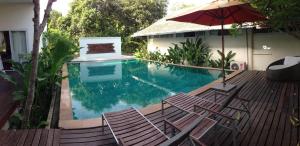 a swimming pool with two chairs and an umbrella at Nakara Samui-Superior Beach front in Ban Thong Phlu
