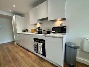 een kleine keuken met witte kasten en een magnetron bij Luxury 2 bed Apartment Bracknell in Bracknell +41 foto's