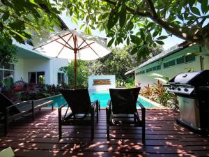 a patio with chairs and an umbrella and a swimming pool at Nakara Samui-Superior Beach front in Ban Thong Phlu