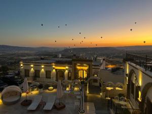 a view of a building with tables and umbrellas at sunset at Zafora Cave Suites Hotel Cappadocia in Uçhisar