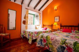 two beds in a room with orange walls at Casa Rural Virgen del Rosario in San Juan de la Rambla