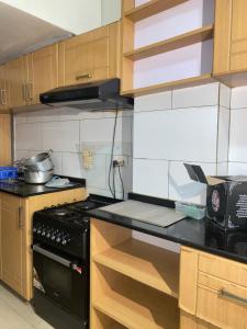 Il comprend une cuisine équipée d'une cuisinière noire et de placards en bois. dans l'établissement Secret Stay inn and hotel, à Kigali