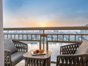 un balcón con 2 sillas y una mesa con fruta. en Sofitel Cairo Downtown Nile, en El Cairo 153 fotos más