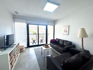 Una sala de estar con un sofá negro y un televisor. en AZUL, en Bolnuevo