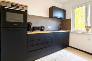 a kitchen with blue cabinets and a black appliance at City Apartment in ruhiger Lage mit Balkon Siegen Parkplatz WLAN Autobahn in Siegen +4 photos