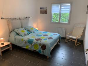 a bedroom with a bed and a chair in it at Villa jacuzzi entre Lac et Ocean in Cazaux