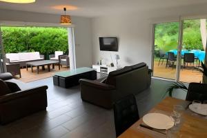 a living room with couches and a dining room at Villa jacuzzi entre Lac et Ocean in Cazaux