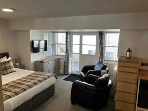 a bedroom with a bed and two chairs and a television at The Penthouse Self Catering in Nairn