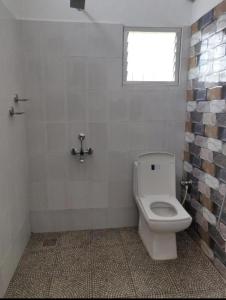a bathroom with a white toilet and a window at Sun Farm Retreat in Auroville