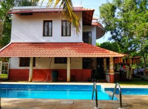 a house with a swimming pool in front of it at Sun Farm Retreat in Auroville +15 photos