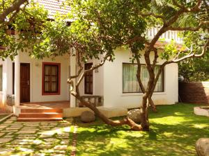a house with a tree in the yard at Sun Farm Retreat in Auroville