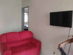 a living room with a red couch and a flat screen tv at Apartamento com 3 quartos a só 200 metros da Basílica in Aparecida