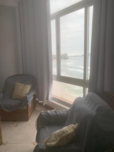 a bedroom with a large window with a view of the ocean at Pitangueiras Condomínio Sobre as Ondas in Guarujá