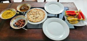 una mesa de madera cubierta con platos y tazones de comida en place of the jungle, en Hiriketiya