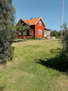 a red house in a field with a yard at Countryside Farm With Pool In Västergötland in Ljung +22 photos
