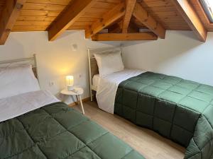two beds in a room with wooden ceilings at Stone House Bourgos in Koroni