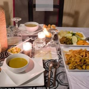 a table with plates of food and a bowl of soup at Sunlight Luxury Desert Camp in Merzouga