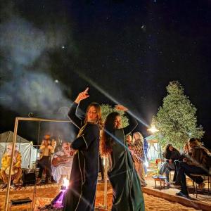 two women are standing in front of a crowd at Sunlight Luxury Desert Camp in Merzouga