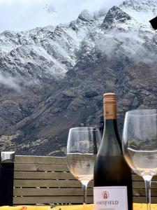 a bottle of wine and two wine glasses on a table at Queenstown Studio with Mountain Views in Frankton