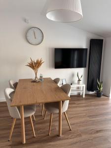 a dining room table with chairs and a clock on the wall at Apartament Stara Środa in Środa Wielkopolska