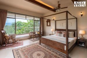a bedroom with a canopy bed and a large window at StayVista at Belmonte with Bonfire, Jacuzzi in Karjat