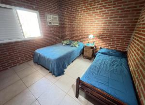 a bedroom with two beds and a brick wall at Casaquinta grande con pileta y parrilla in Camba Punta