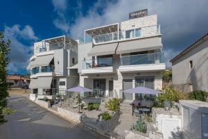 a building with tables and umbrellas in front of it at Imagine Studios in Paliouri