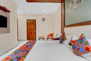 a bedroom with a large white bed with colorful pillows at FabHotel Kayal Plaza in Coimbatore