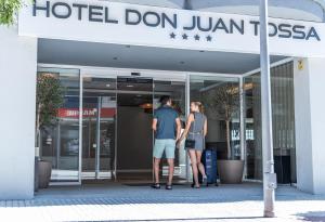 Dos personas de pie frente a un hotel Don Jumeirah. en Hotel Don Juan Tossa, en Tossa de Mar