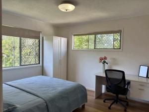 a bedroom with a bed and a desk and a chair at Welcome to your leafy retreat in Graceville! in Brisbane