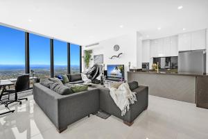 a living room with a gray couch and a kitchen at Sky-High Villa with Wide Ocean Views - Pet Friendly in Gold Coast