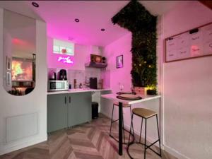 een keuken met roze verlichting en een tafel en krukken bij Secret Room Elegance, mystère et intimité in Souppes-sur-Loing