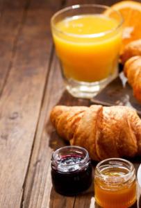 a wooden table with a glass of orange juice and croissants at Hotel Villa Maya in Saint-Tropez