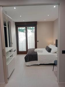 a white bedroom with a bed and a window at Aptos Living Libreros climatizados in Salamanca